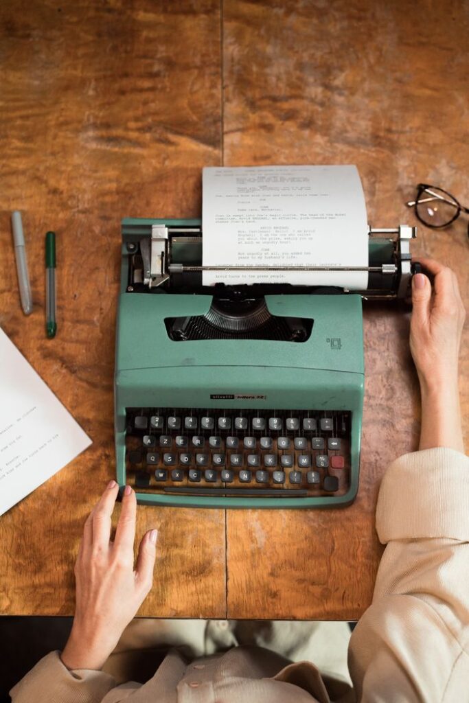 The Art of Drawing Readers In: Your attractive post title goes here A overhead shot of hands typing on a vintage typewriter, set on a wooden desk.